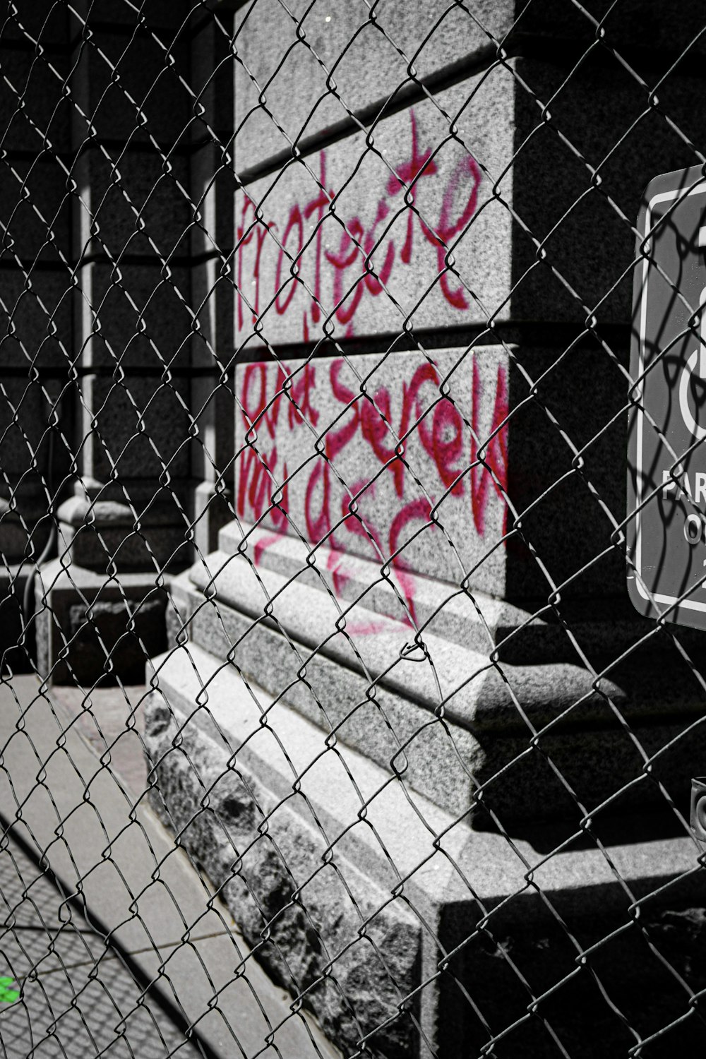 a black and white photo of graffiti on a fence
