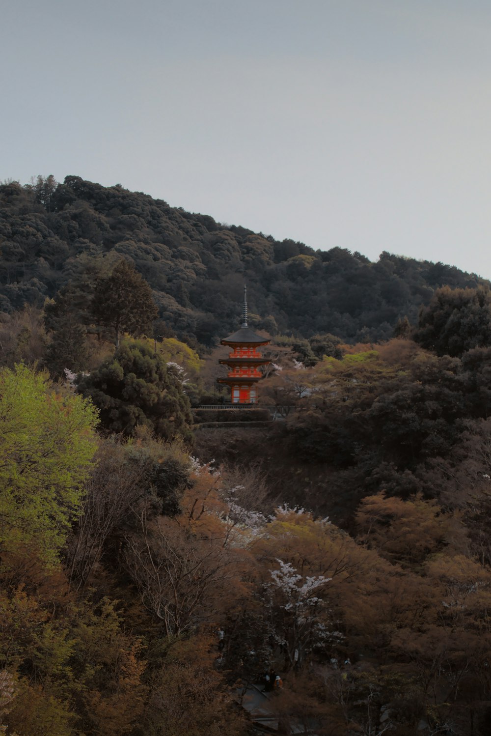 Una pagoda roja en la cima de una colina rodeada de árboles