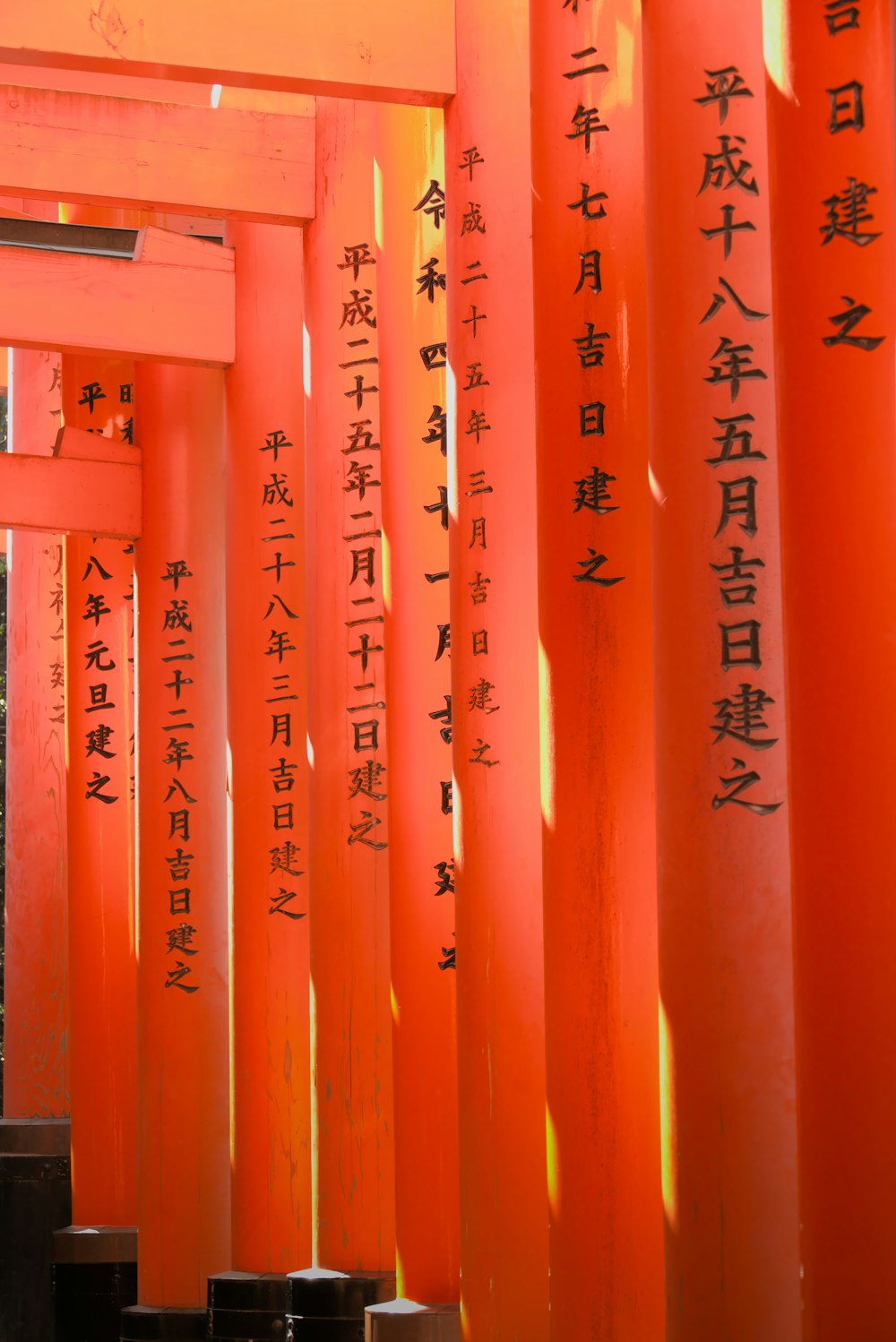 Una fila de columnas naranjas con escritura asiática en ellas