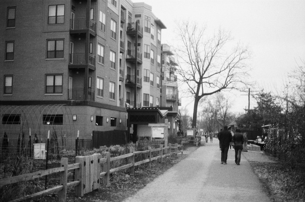 a man walking down a sidewalk next to a tall building