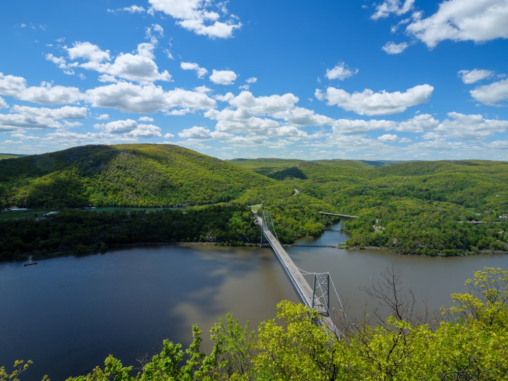 a bridge over a river surrounded by lush green hills