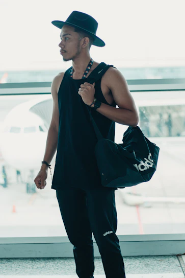 A confident student holding a passport and acceptance letter, standing in front of an international airport.