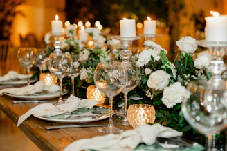 a table set for a formal dinner with white flowers and candles