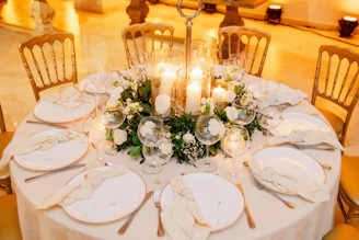 a table set with white plates and candles