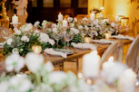 A tastefully decorated wedding table with candles and floral centerpieces in soft hues.