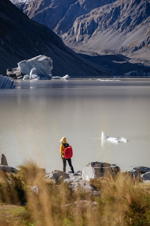 A happy traveler standing by a serene lake in Patagonia, surrounded by towering peaks.