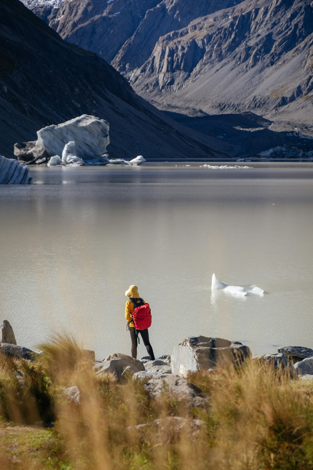 a person with a backpack standing on a rock near a lake