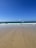 A serene beach view with gentle waves and soft sand under a clear blue sky.