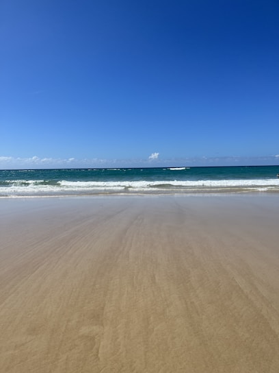 A serene beach scene with soft sand and gentle waves, perfect for a day out.