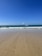 A serene beach view with gentle waves and soft sand under a clear blue sky.