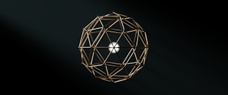 A geometric structure composed of interconnected golden rods forms a spherical shape against a dark background, with a white circular center providing contrast.