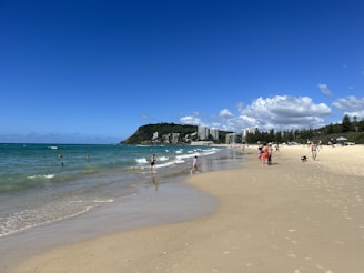 A sunny beach in São Paulo with clear blue water and people enjoying the shore.