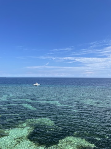 Researchers collecting marine samples on a boat under a clear blue sky.