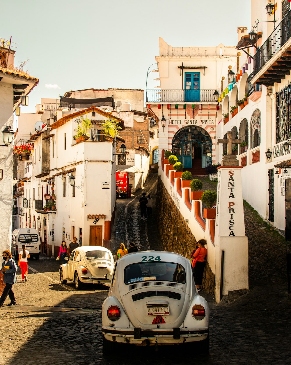 a white car driving down a street next to tall buildings