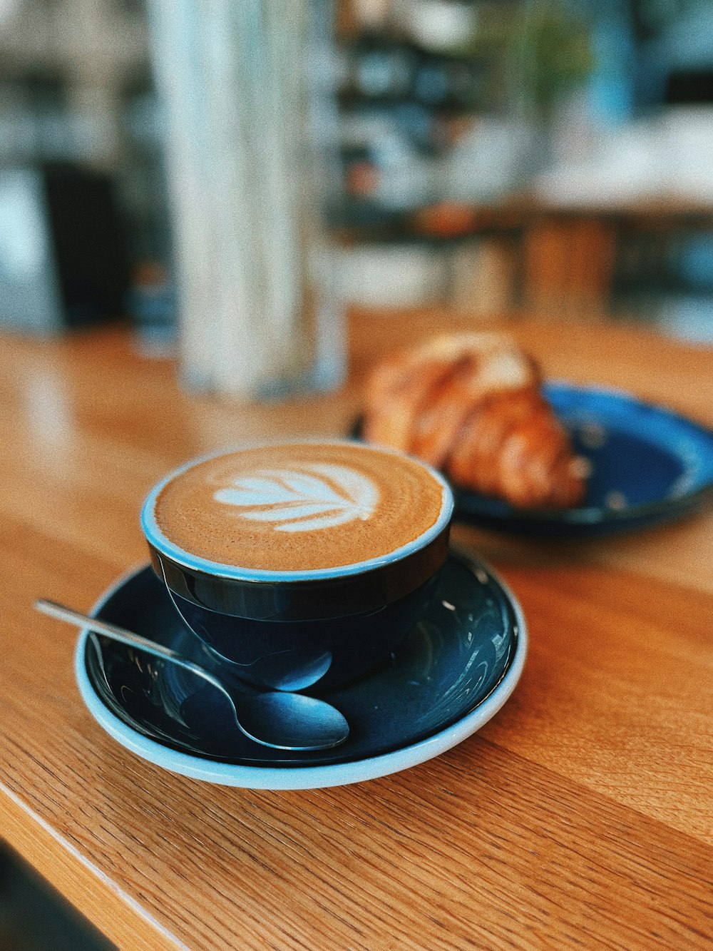 a cappuccino and croissant on a wooden table