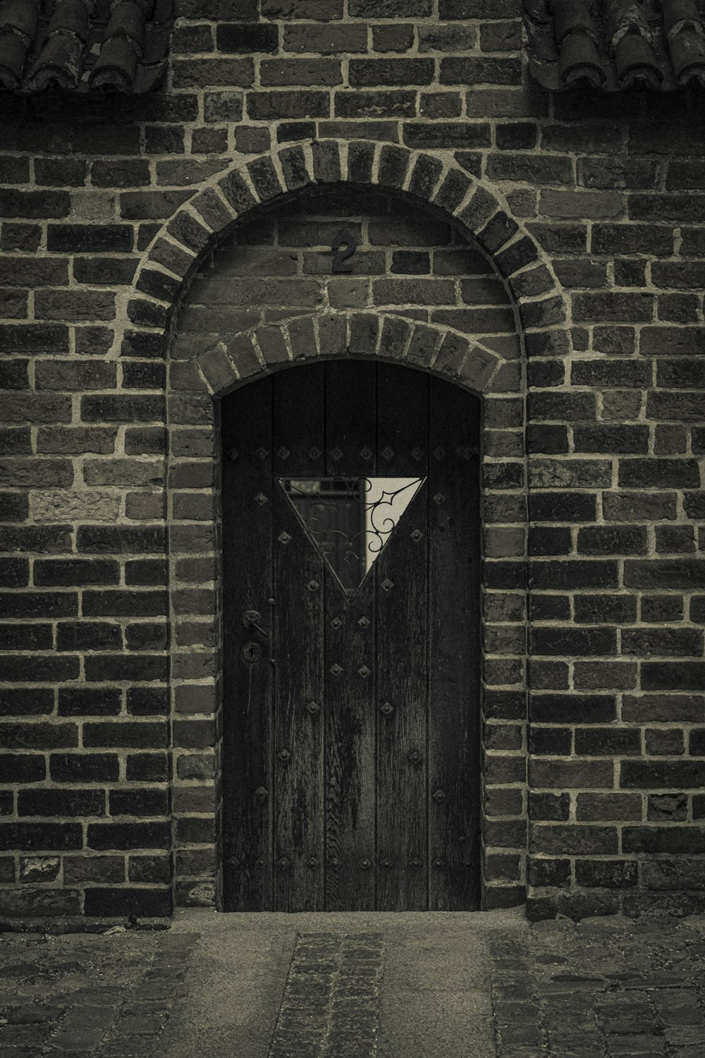 a black and white photo of a door and a brick wall