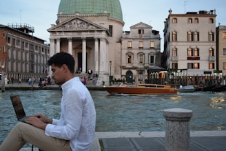 a man sitting on a ledge using a laptop