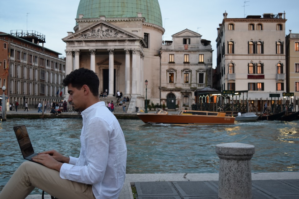 a man sitting on a ledge using a laptop