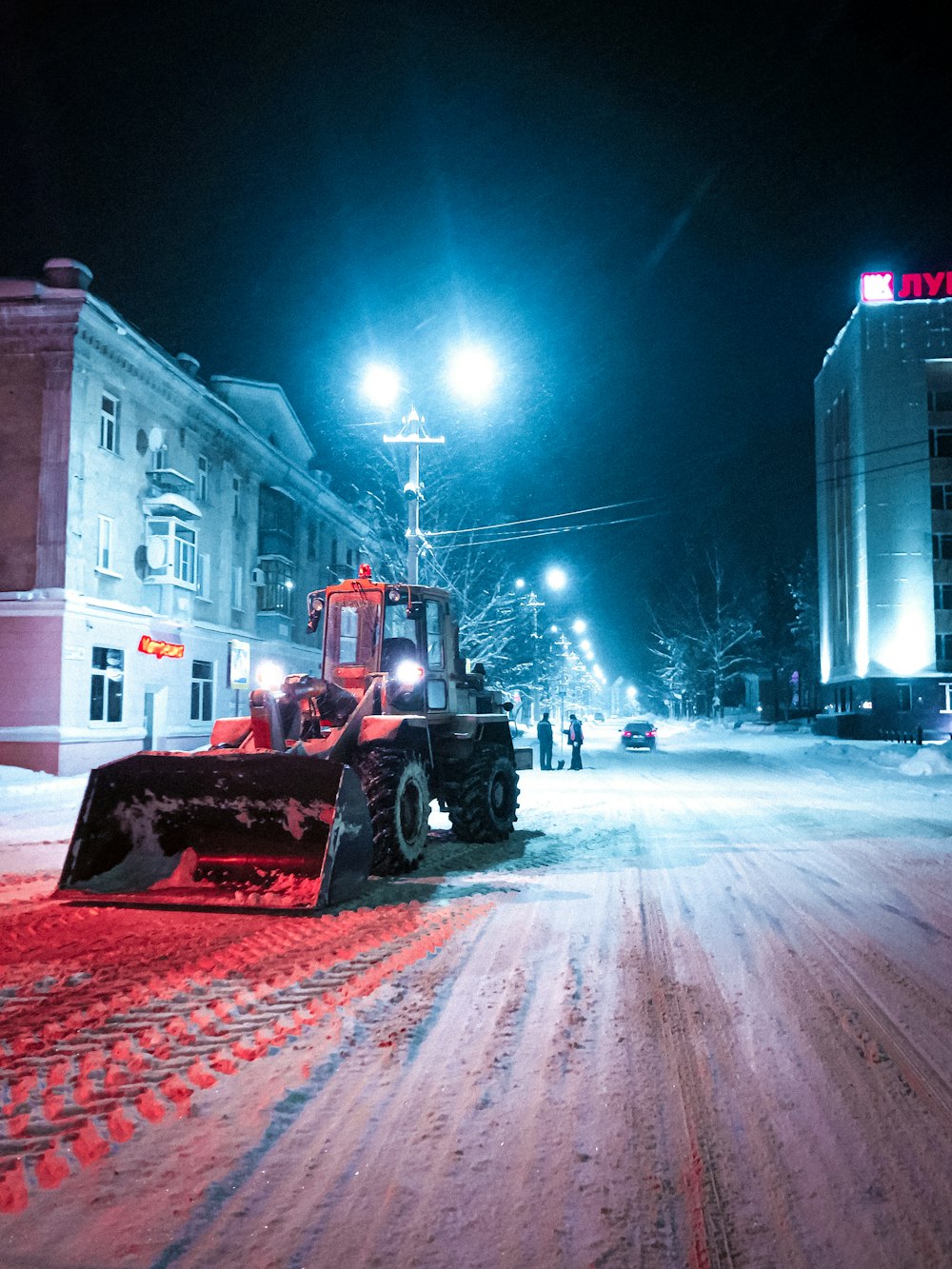 a snow plow on a snowy street at night