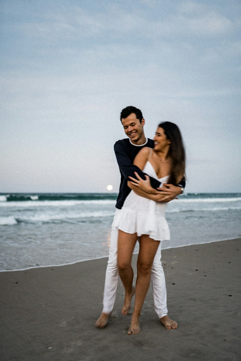 a man holding a woman on the beach