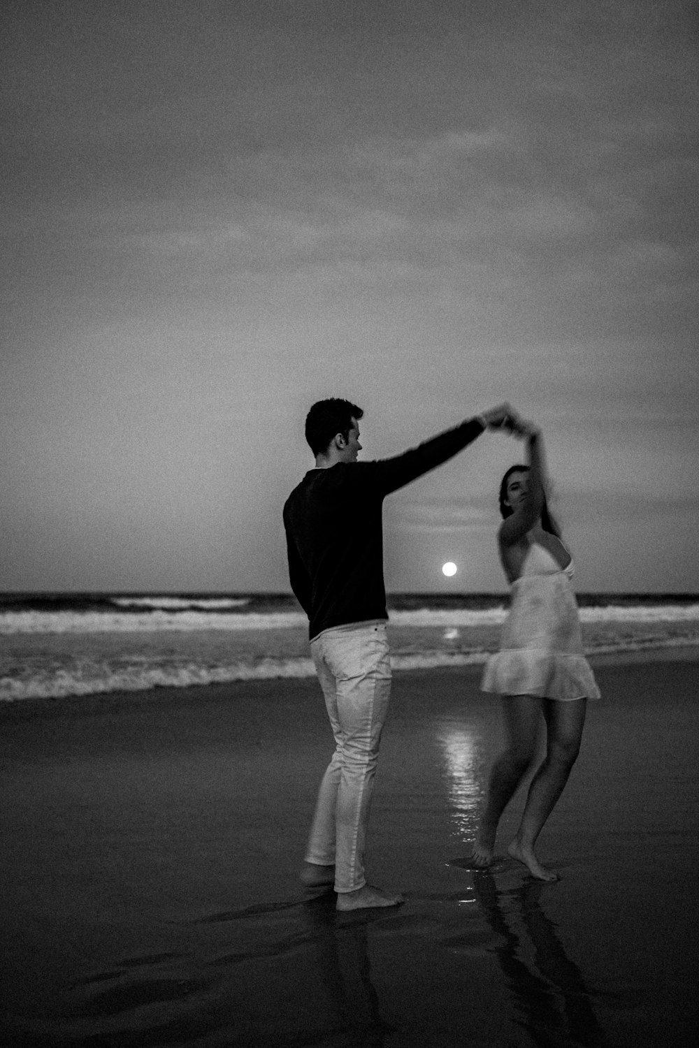 um homem e uma mulher dançando na praia