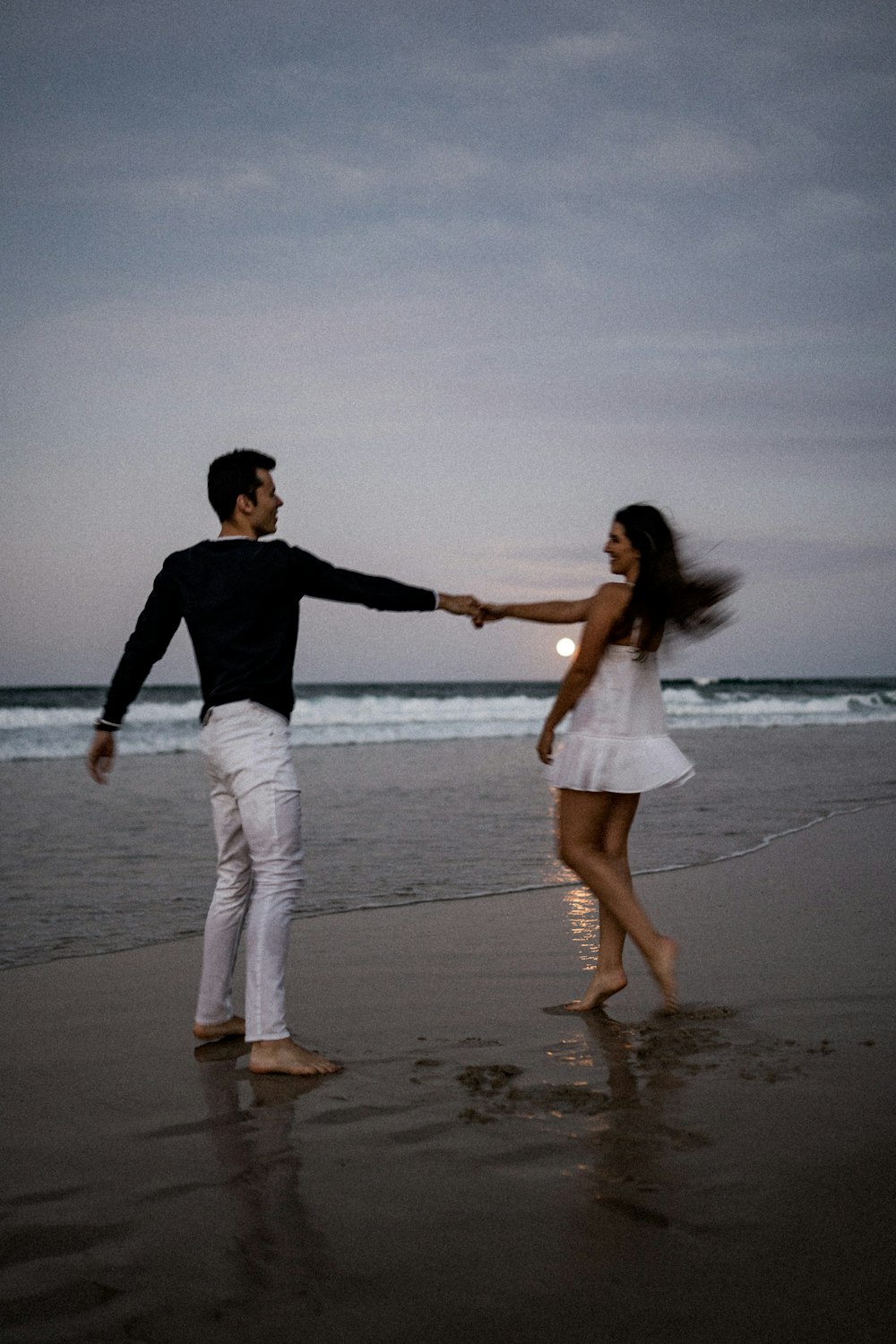 um homem e uma mulher de mãos dadas em uma praia