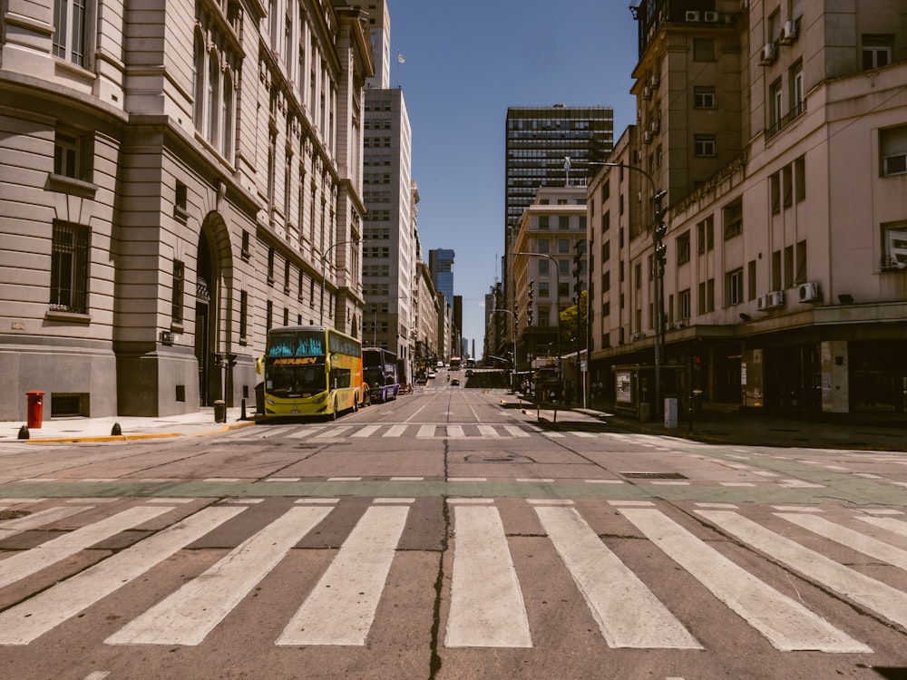 a yellow bus driving down a street next to tall buildings