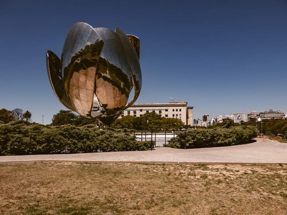 a large metal sculpture in a park with buildings in the background