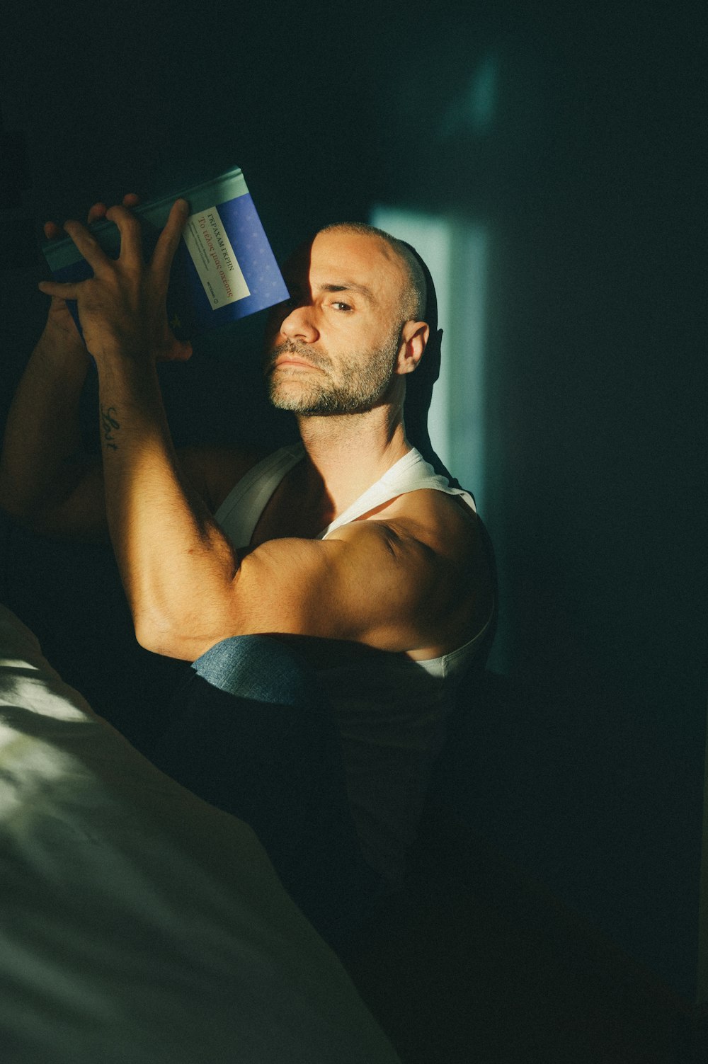 a man in a tank top drinking from a cup
