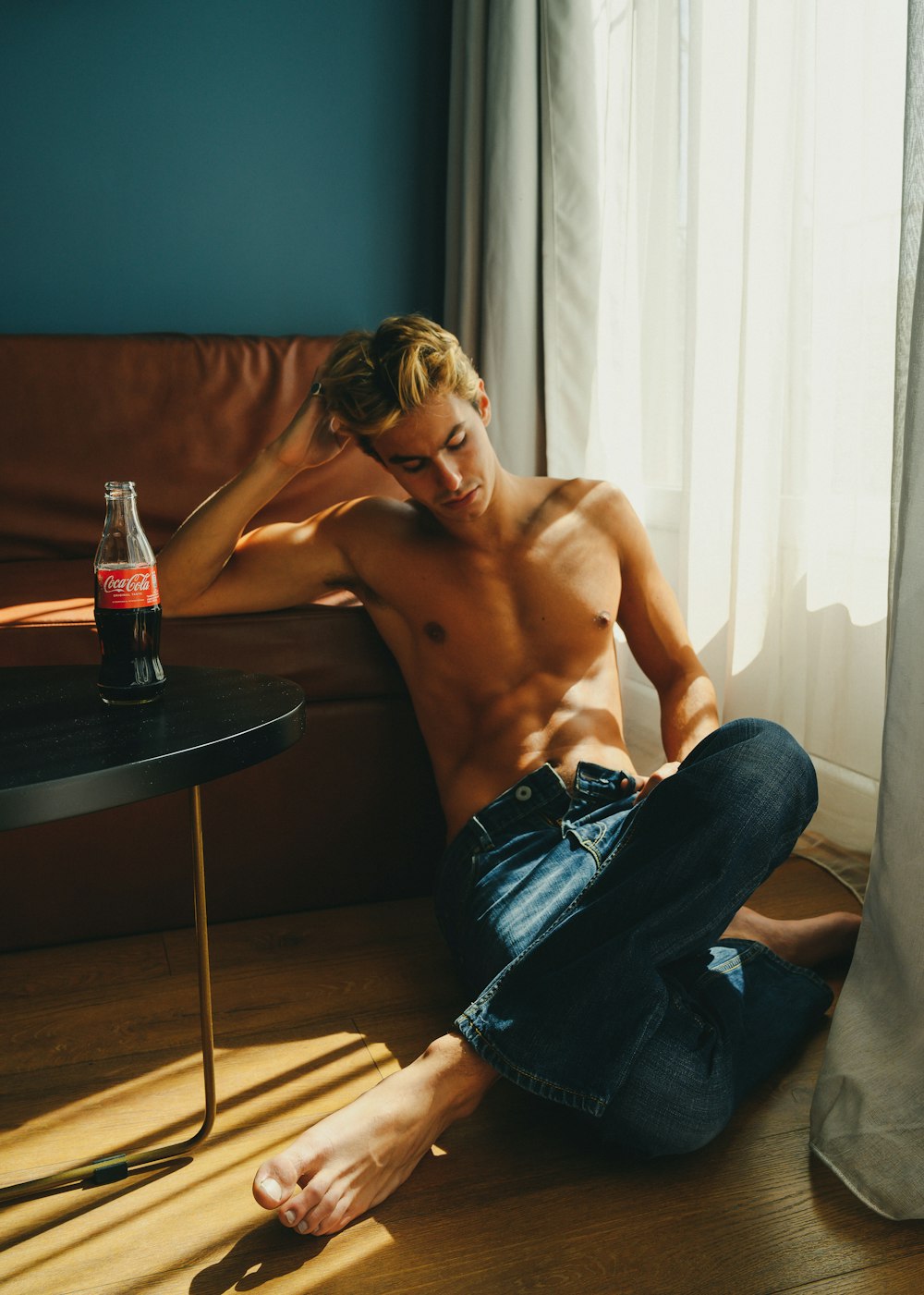 a shirtless man sitting on the floor next to a table