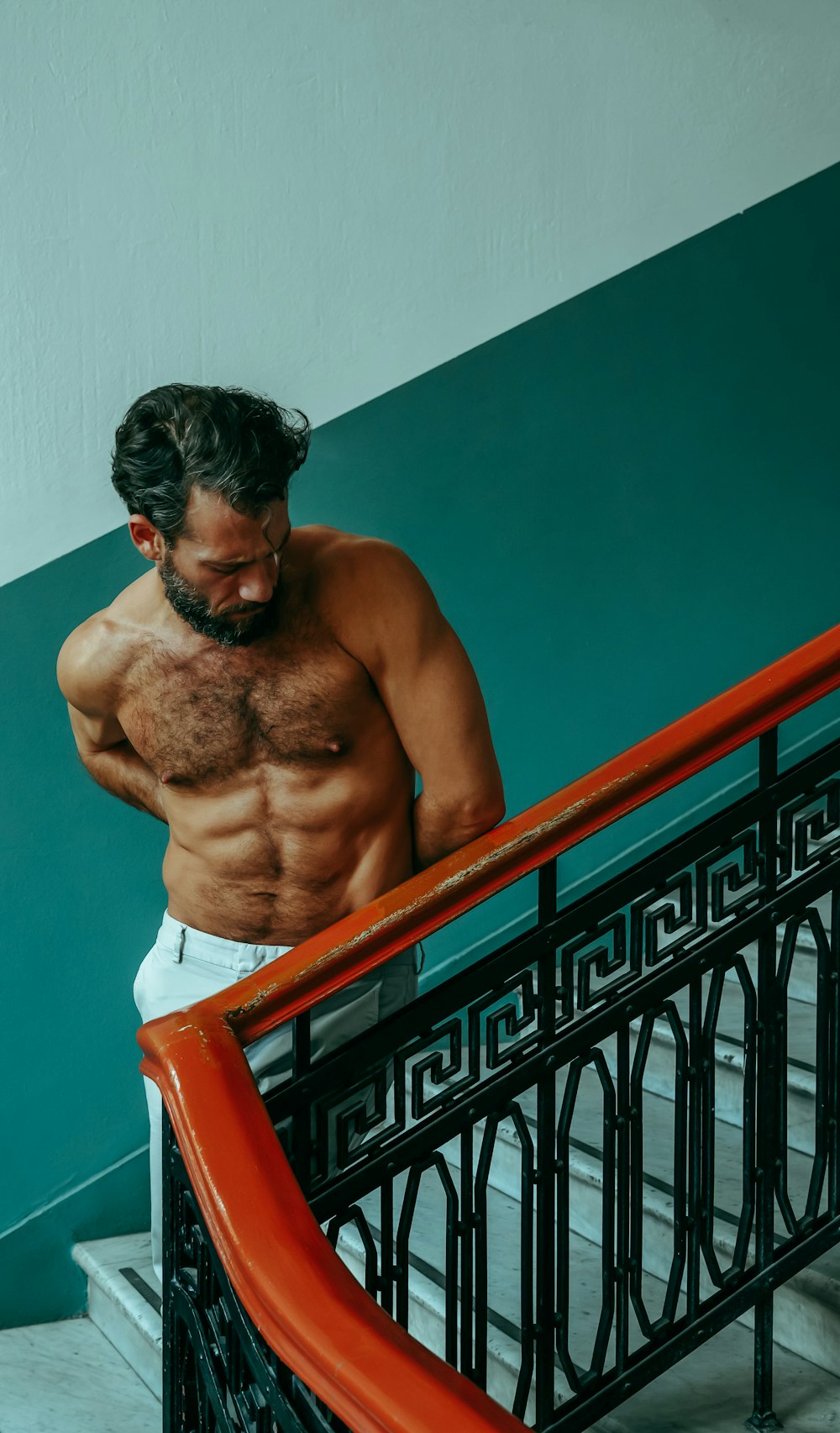 a shirtless man leaning against a railing