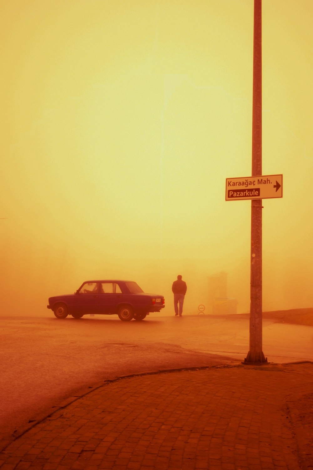 霧の通りで車の隣に立っている男