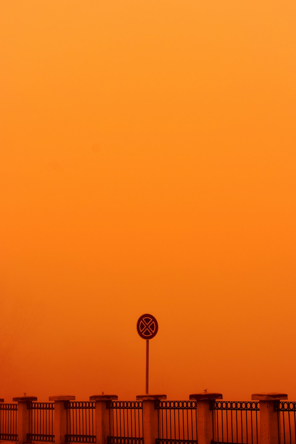 an orange sky with a street sign in the foreground