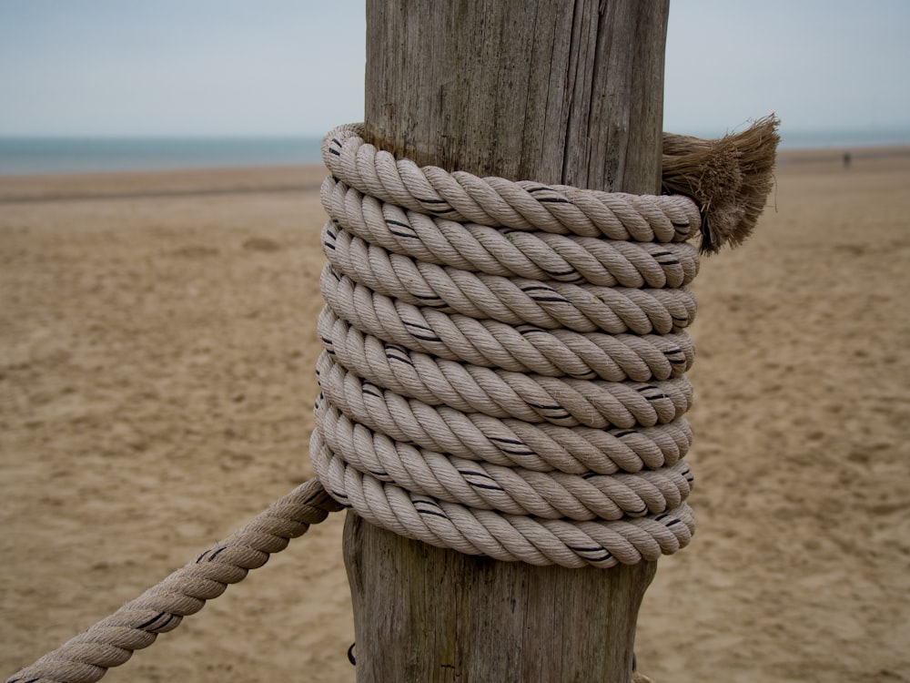 a rope wrapped around a wooden post on a beach