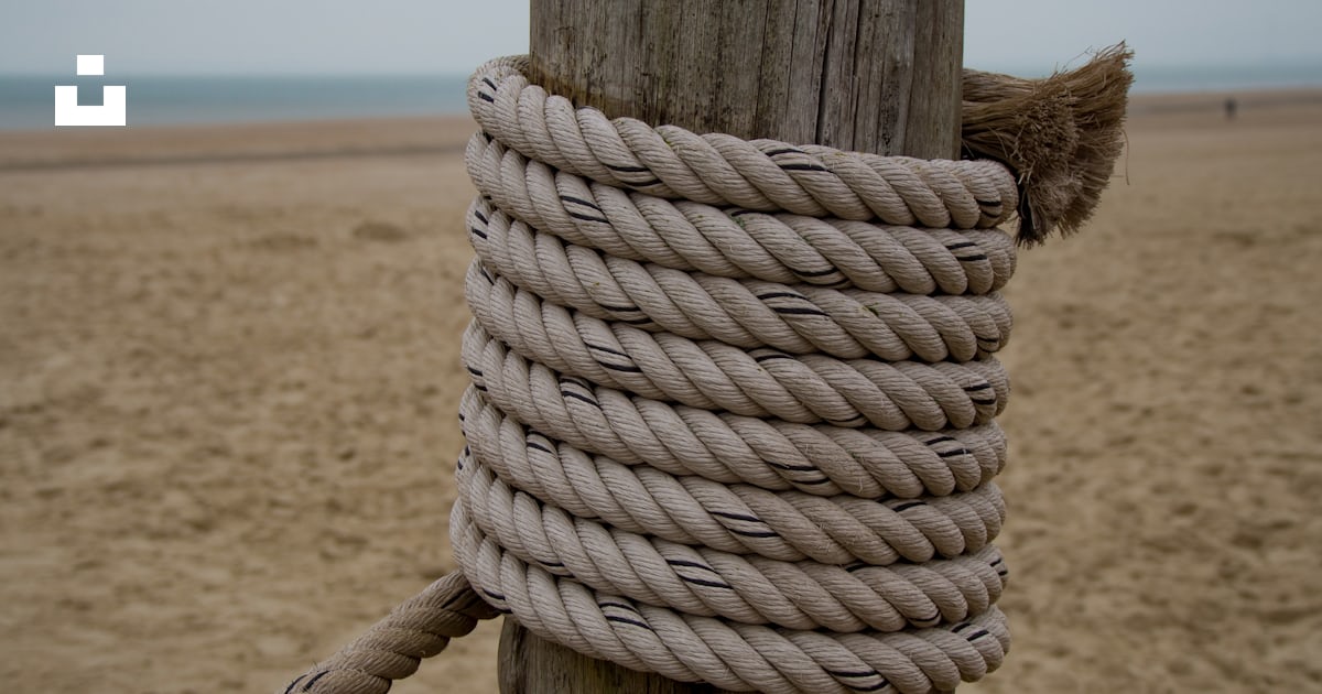 A rope wrapped around a wooden post on a beach photo – Free Rope Image ...