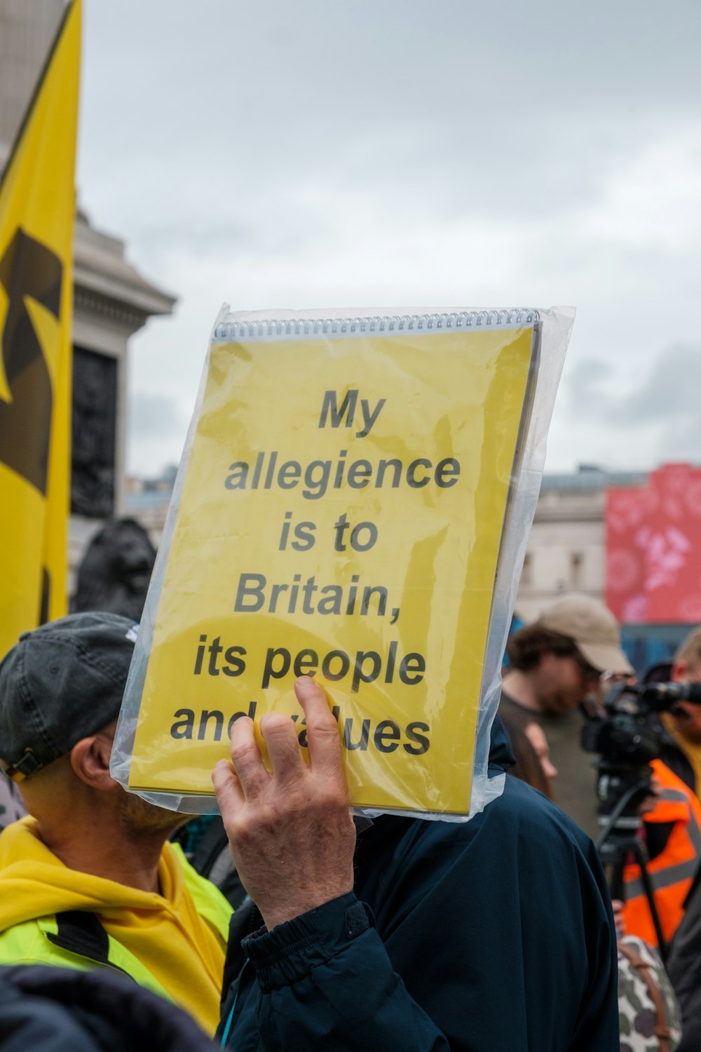 a man holding a sign that says my allegiance is to britain, its people and