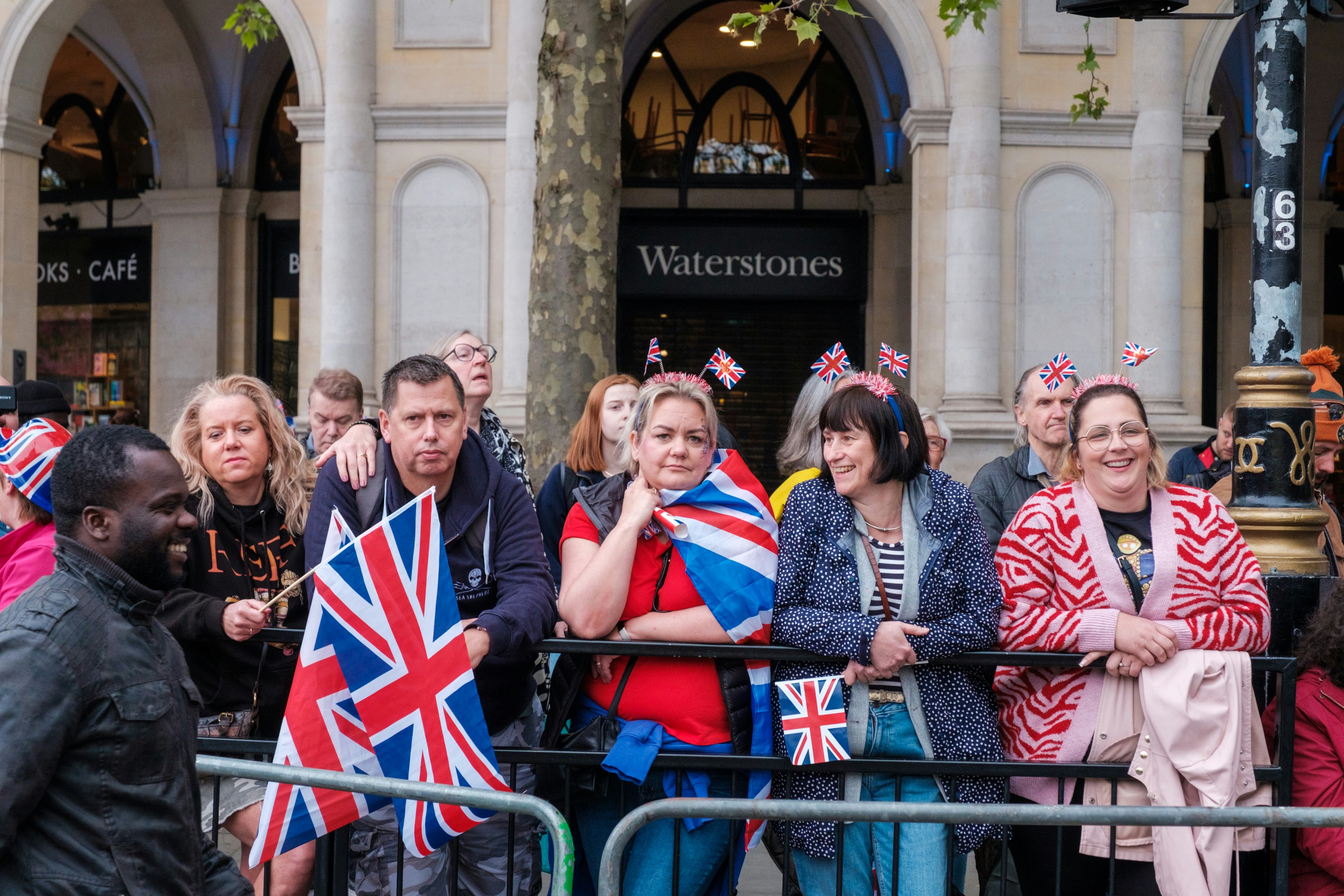 Un grupo de personas con banderas británicas frente a un edificio