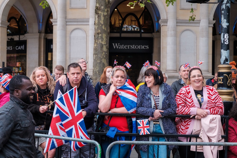 Un groupe de personnes tenant des drapeaux britanniques devant un bâtiment