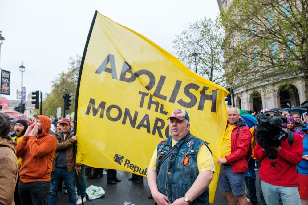 a man standing in front of a group of people holding a yellow sign