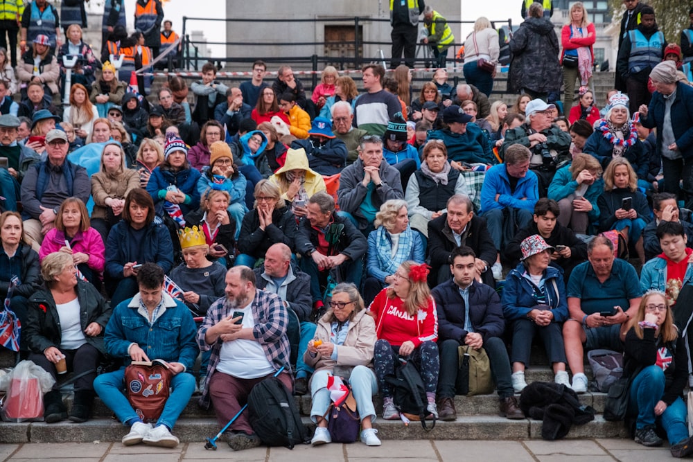 un grand groupe de personnes assises sur des marches devant un bâtiment