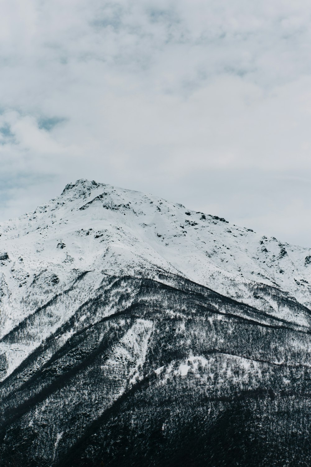 a mountain covered in snow under a cloudy sky