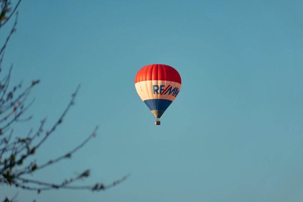a red, white and blue hot air balloon flying in the sky
