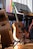 A wooden acoustic guitar rests against a stand next to a Yamaha keyboard and a music stand with sheet music. Various colorful objects are in the background, adding vibrancy to the scene. The lighting casts a warm glow on the instruments, enhancing the cozy ambiance.