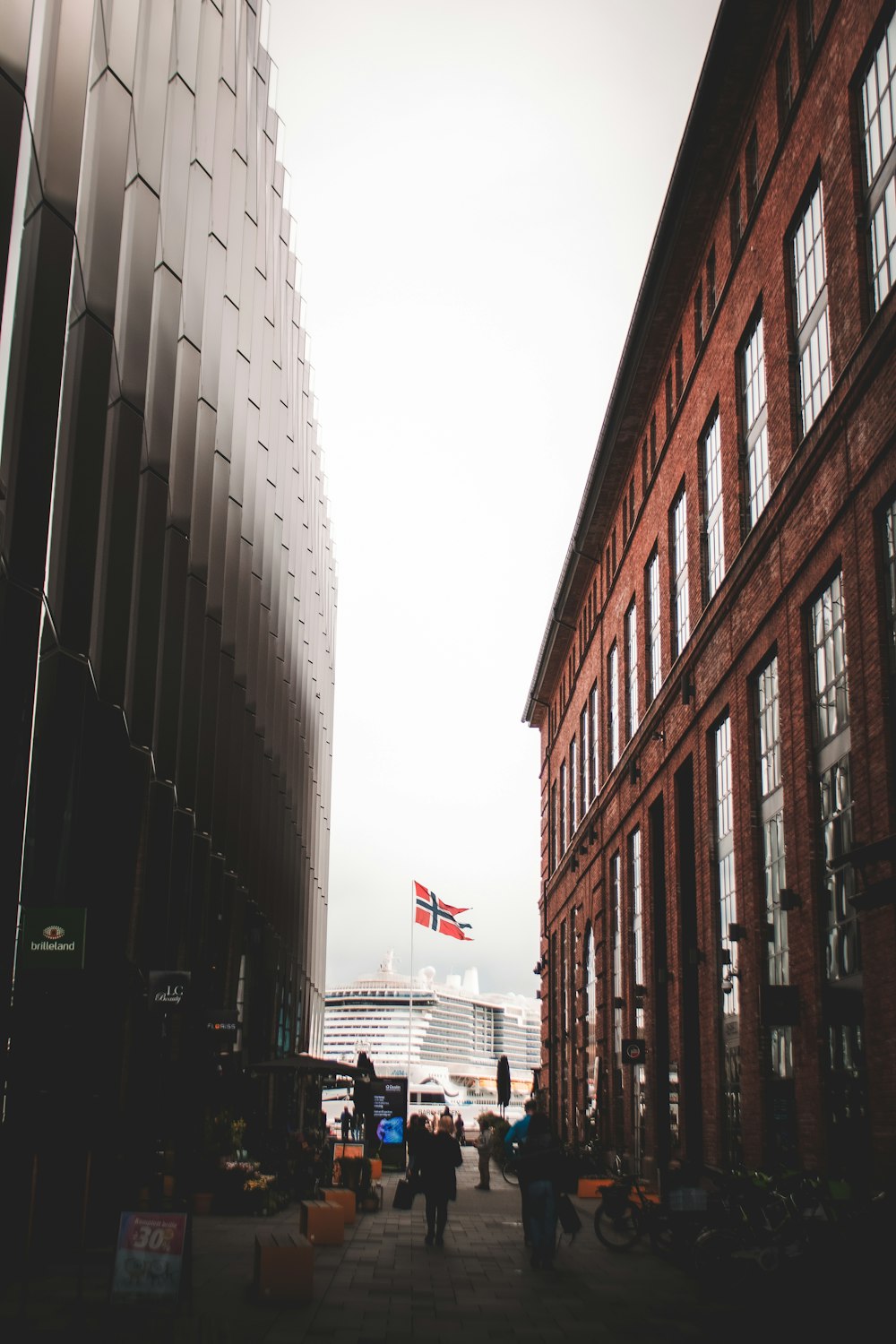 a group of people walking down a street next to tall buildings