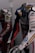 Two motorcycle racing suits are displayed side by side, adorned with various sponsor logos and designs. The suit in the foreground features logos such as Xerox, AMD, and Shell, and has a color scheme of red, blue, and white with intricate graphics. A helmet with a striking design can be seen at the bottom of the display.