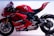 A sleek, red racing motorcycle featuring several sponsor logos such as Lenovo and NetApp. The bike has a streamlined design with a prominent windshield and visible mechanical components. Its rear swingarm and large rear tire indicate its high-performance capabilities.