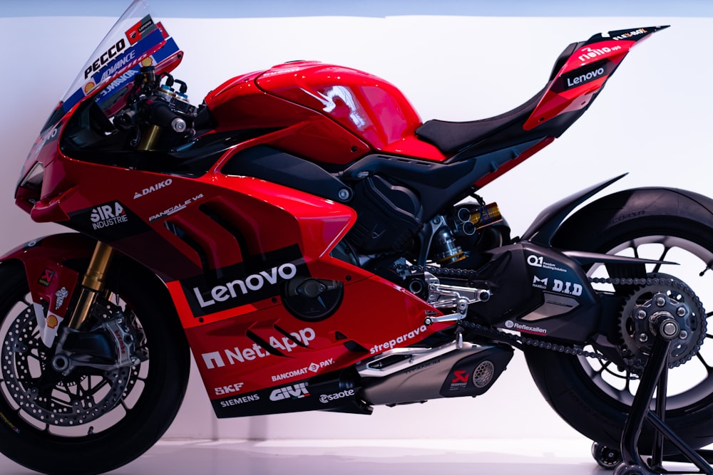 a red motorcycle parked in front of a white wall