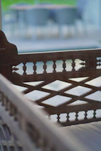 Elegant wooden bench with grapevine leaves softly blurred in the background.