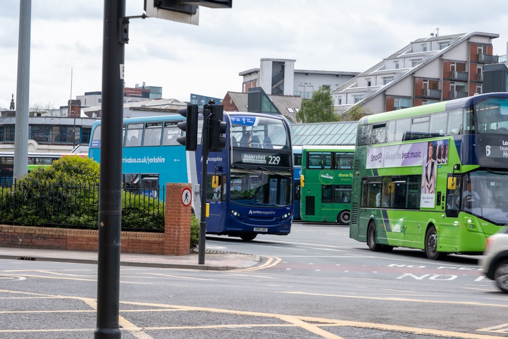 a couple of green double decker buses driving down a street