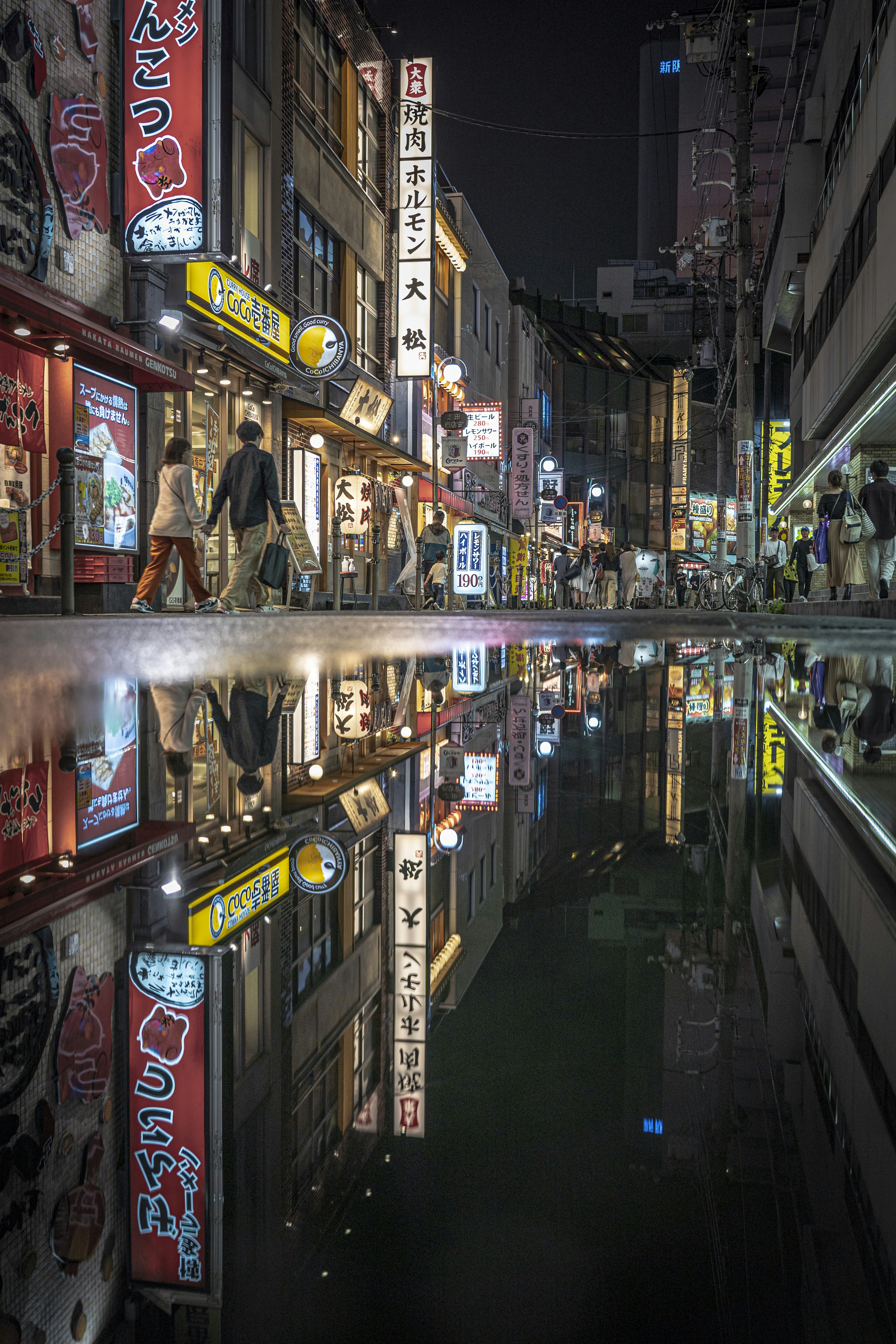a city street at night with a reflection in the water